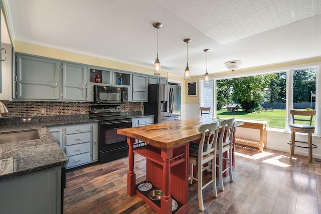 kitchen featuring black appliances, decorative backsplash, dark hardwood / wood-style flooring, and hanging light fixtures