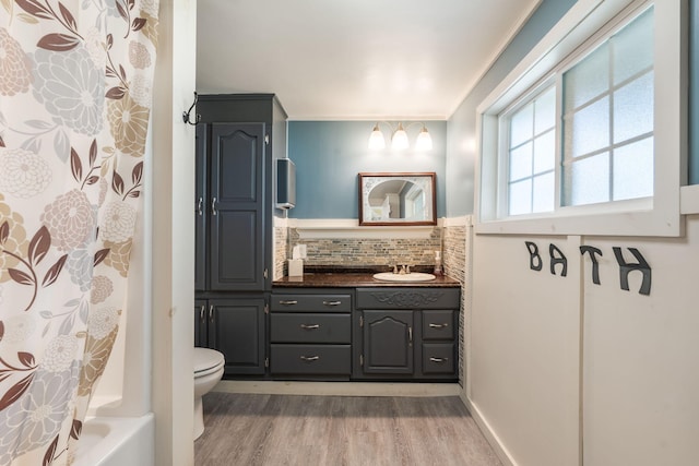 full bathroom featuring hardwood / wood-style floors, shower / tub combo with curtain, toilet, vanity, and backsplash