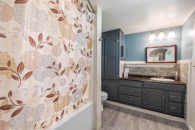 full bathroom featuring toilet, crown molding, backsplash, vanity, and hardwood / wood-style floors