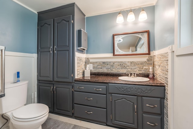 bathroom with hardwood / wood-style floors, backsplash, vanity, and toilet