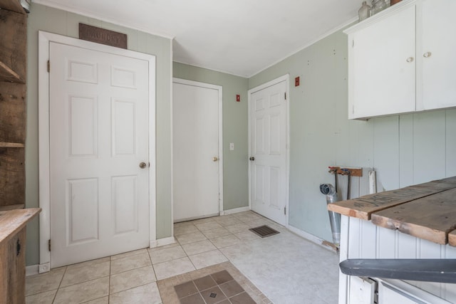 interior space featuring crown molding, light tile patterned flooring, and white cabinetry