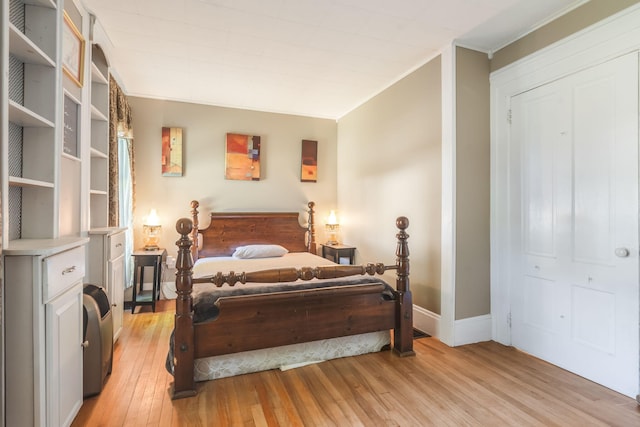 bedroom with crown molding, light wood-type flooring, and a closet