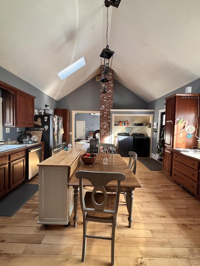 kitchen with light hardwood / wood-style flooring, butcher block counters, lofted ceiling with skylight, stainless steel appliances, and a kitchen island