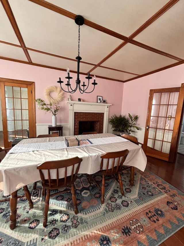 dining space with dark hardwood / wood-style floors, an inviting chandelier, and a fireplace