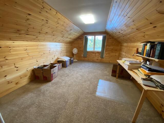 additional living space featuring carpet, vaulted ceiling, wooden ceiling, and wood walls