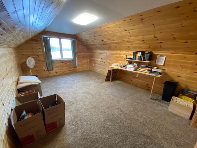 bonus room featuring carpet flooring, vaulted ceiling, wood ceiling, and wooden walls