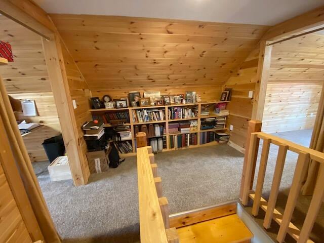 interior space with carpet, lofted ceiling, and wooden walls