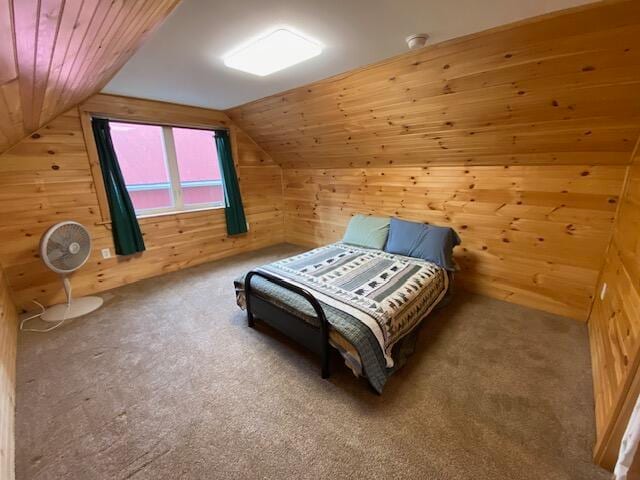 bedroom featuring vaulted ceiling, wooden walls, and carpet flooring