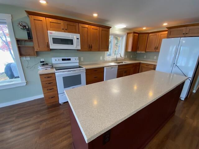 kitchen featuring sink, white appliances, a kitchen island, and dark hardwood / wood-style floors