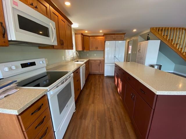 kitchen featuring a center island, sink, white appliances, and dark wood-type flooring