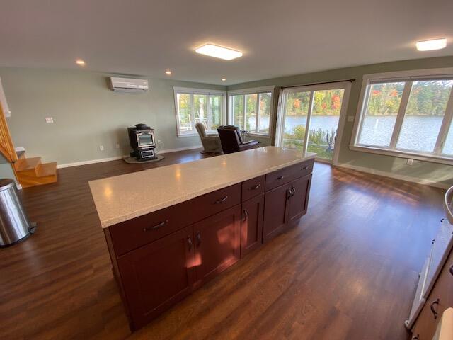 kitchen featuring a wood stove, dark hardwood / wood-style flooring, a kitchen island, and a wall unit AC