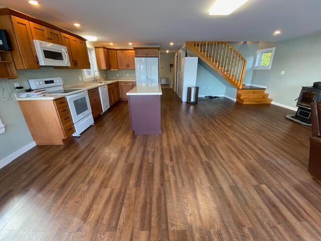 kitchen with white appliances, a kitchen island, dark hardwood / wood-style floors, and a wood stove