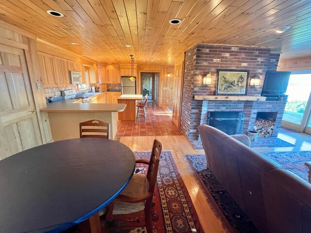 dining area featuring light hardwood / wood-style flooring, a fireplace, brick wall, and wood ceiling