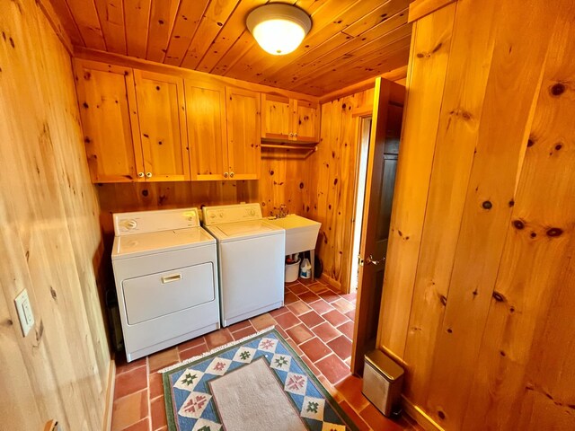 clothes washing area with cabinets, tile patterned floors, wood walls, washing machine and clothes dryer, and wood ceiling