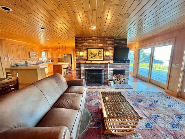 living room featuring wooden ceiling, brick wall, and a brick fireplace