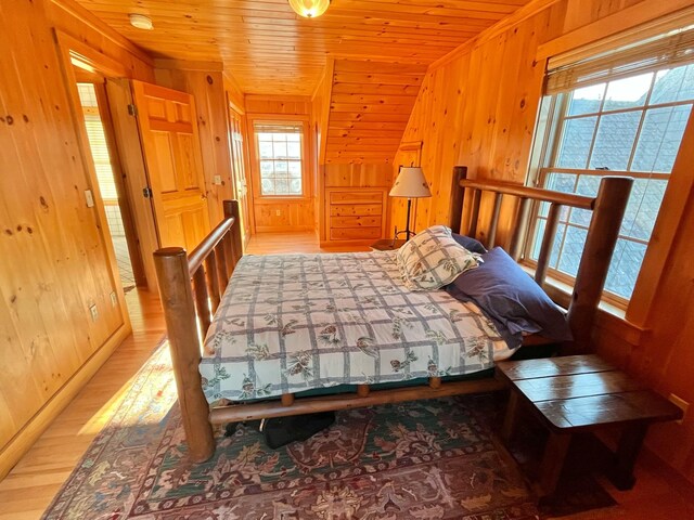 bedroom with light wood-type flooring, vaulted ceiling, wooden walls, and wood ceiling