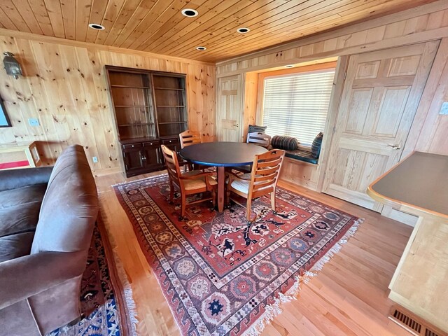 dining room featuring wooden ceiling, wooden walls, and hardwood / wood-style flooring