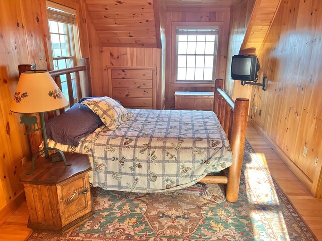 bedroom with wood-type flooring and wooden walls