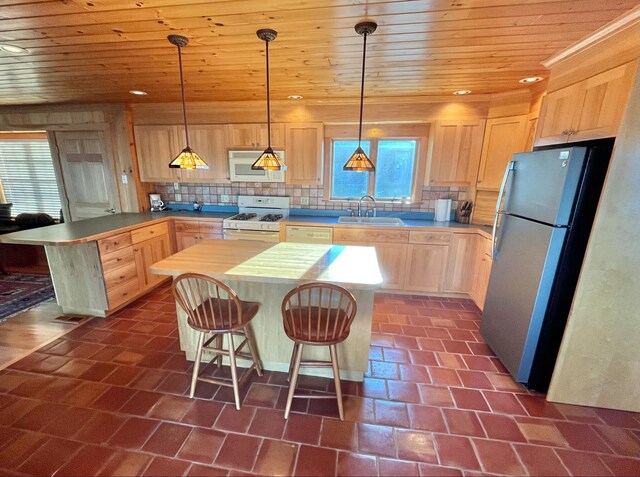 kitchen with white appliances, decorative backsplash, a kitchen island, and light brown cabinetry