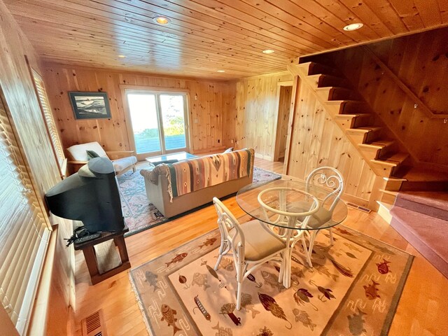 living room with wood walls, wood ceiling, and light hardwood / wood-style floors