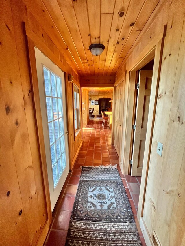 corridor featuring wood walls, tile patterned flooring, and wooden ceiling