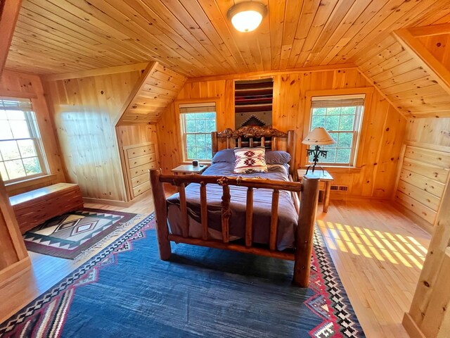 bedroom with hardwood / wood-style floors, wood walls, and lofted ceiling