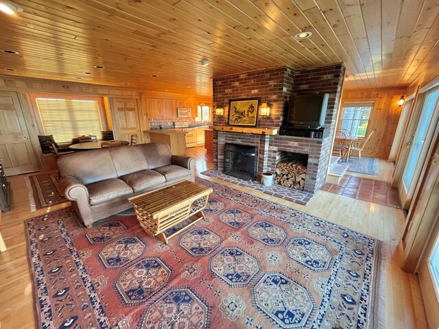 living room with hardwood / wood-style floors, wooden ceiling, a brick fireplace, brick wall, and wood walls