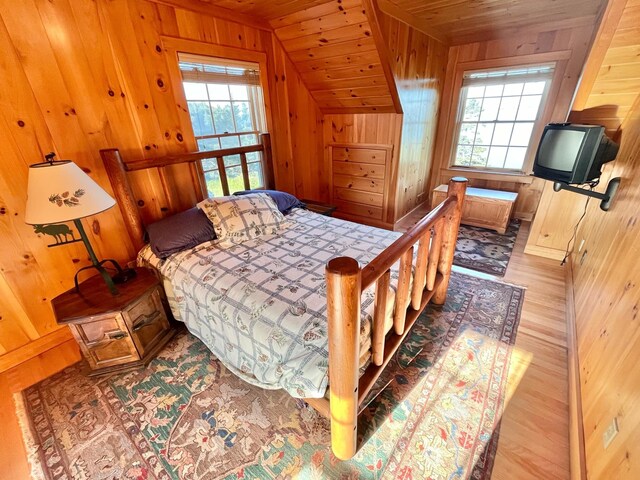 bedroom with wood walls, light hardwood / wood-style flooring, vaulted ceiling, and wood ceiling