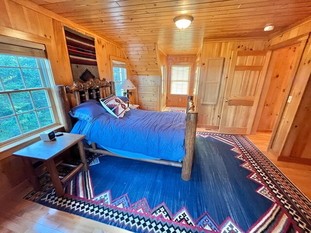 bedroom with wood walls, wood ceiling, hardwood / wood-style floors, and multiple windows