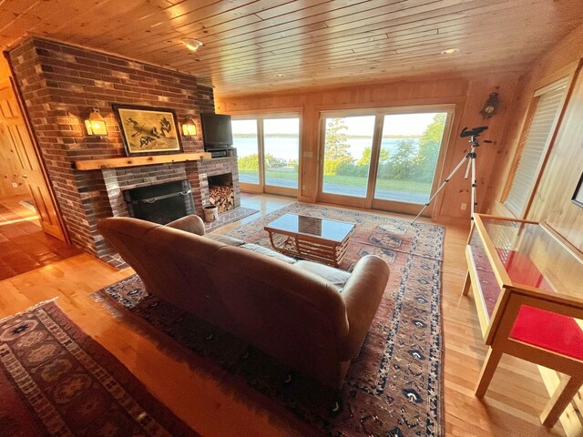 living room with a fireplace, wood walls, light hardwood / wood-style floors, and wood ceiling