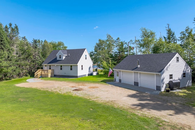 exterior space with a garage, a yard, an outbuilding, and a deck