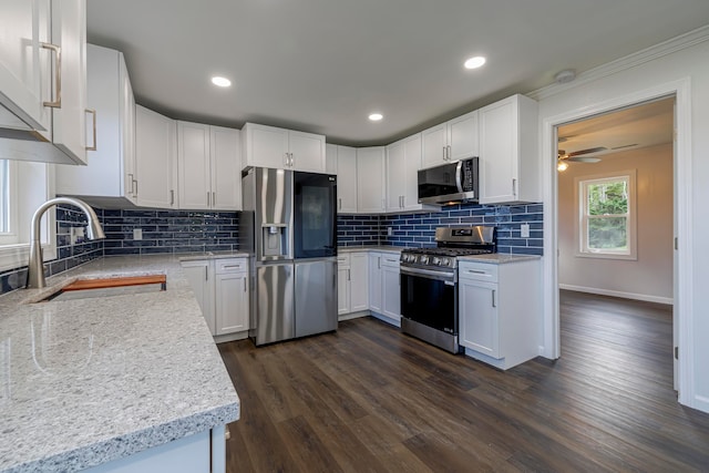 kitchen with appliances with stainless steel finishes, dark hardwood / wood-style floors, decorative backsplash, and white cabinetry