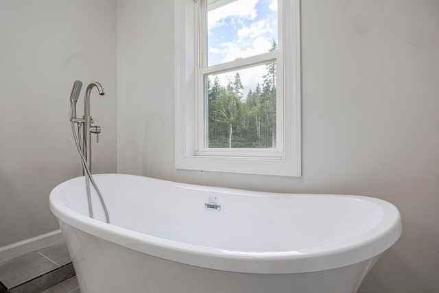 bathroom with a tub to relax in, tile patterned floors, and a healthy amount of sunlight