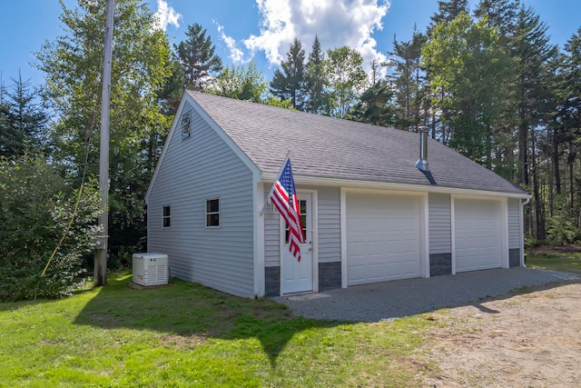 exterior space with a garage, cooling unit, an outbuilding, and a yard