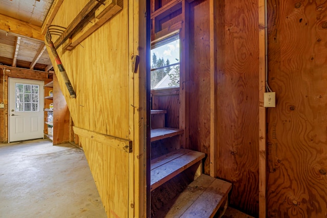 stairs featuring concrete floors, wooden walls, and a wealth of natural light