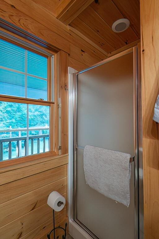 full bathroom with wooden walls, wood ceiling, and a shower stall