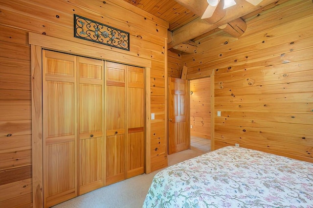 bedroom featuring a closet, a ceiling fan, light carpet, wooden walls, and wooden ceiling