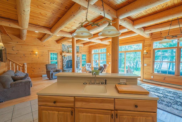 kitchen with wooden walls, a sink, wood ceiling, open floor plan, and beamed ceiling