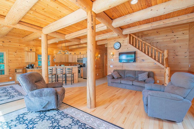 living area with stairway, wood walls, light wood-style flooring, and beamed ceiling
