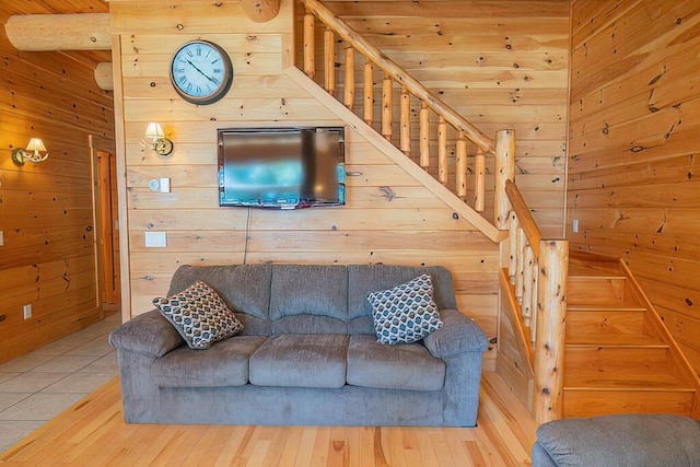 living area with stairs, wood finished floors, and wooden walls