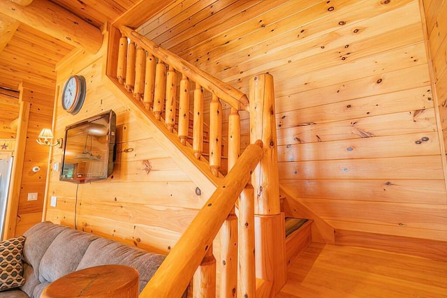stairway with beamed ceiling, a sauna, wood walls, and wood ceiling