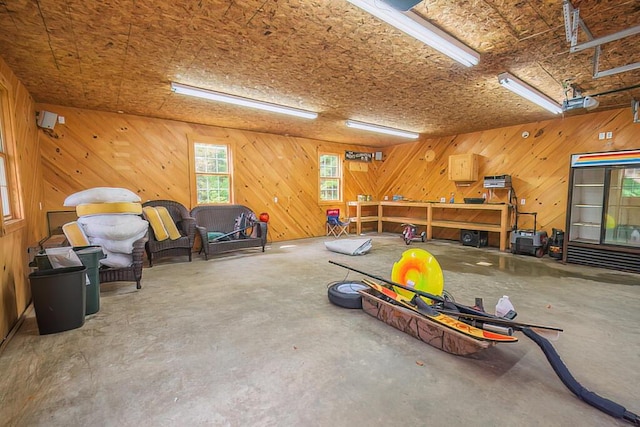 interior space featuring wood walls, a workshop area, and unfinished concrete floors