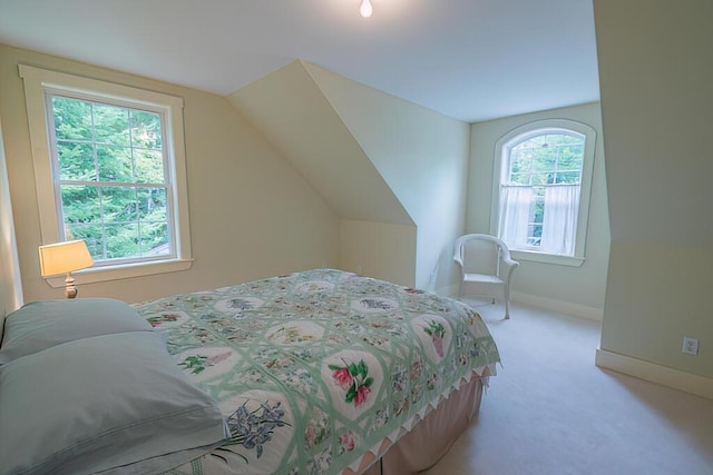 bedroom featuring light carpet, multiple windows, vaulted ceiling, and baseboards