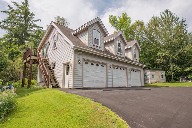 view of side of property featuring a garage, driveway, stairway, and a lawn
