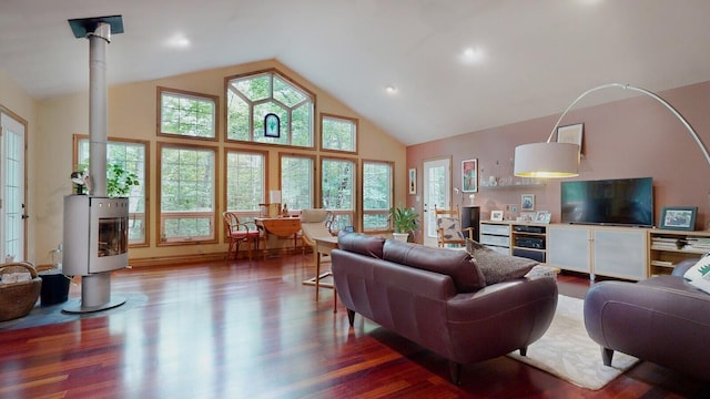 living room with high vaulted ceiling, a wood stove, and wood finished floors