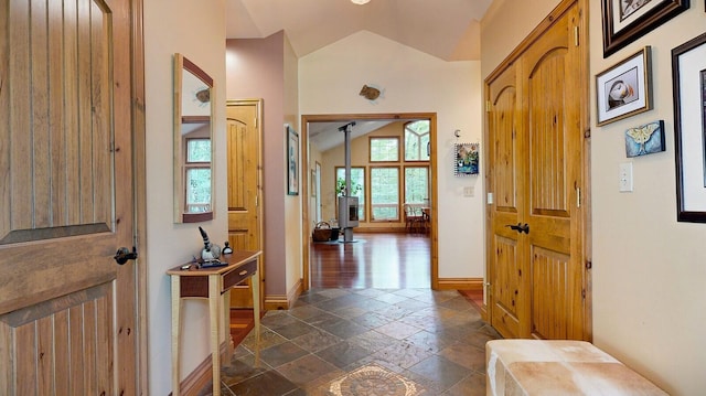 entrance foyer with baseboards, vaulted ceiling, and stone tile flooring