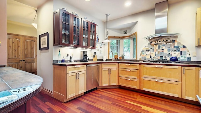 kitchen with stainless steel appliances, hanging light fixtures, range hood, dark countertops, and glass insert cabinets