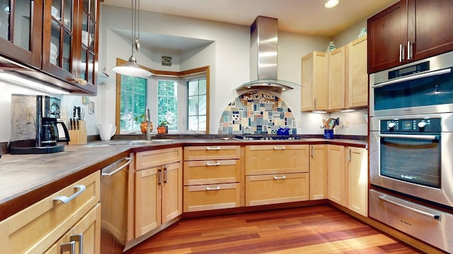 kitchen with stainless steel appliances, hanging light fixtures, a warming drawer, wall chimney exhaust hood, and dark countertops