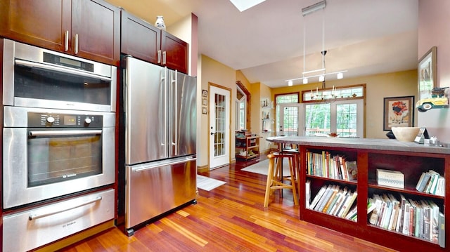 kitchen featuring rail lighting, stainless steel appliances, light wood-style floors, pendant lighting, and a warming drawer