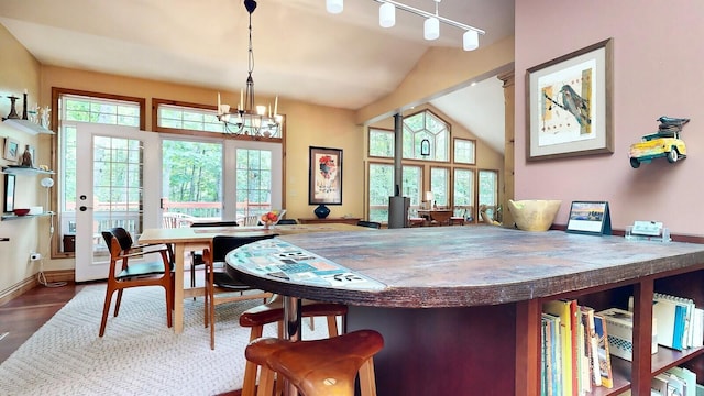 interior space with lofted ceiling, baseboards, wood finished floors, and an inviting chandelier